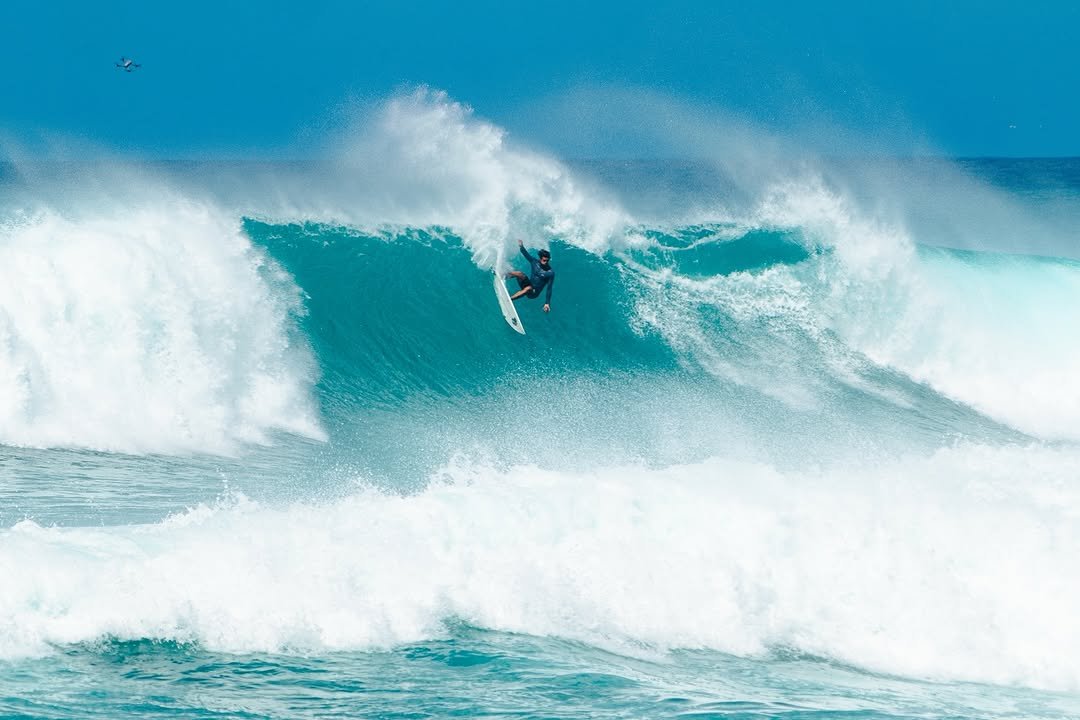 Photo shared by Zeke Lau on August 11, 2025 tagging @olukai, @xcelwetsuits, @mattaleong, @tokorosurfboards, and @darcsportohana. May be an image of 1 person, surfboard, ocean, water and text.