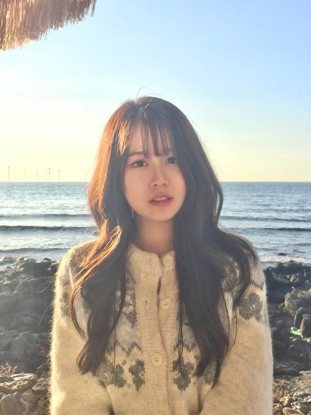 Photo by 지히지히 on December 20, 2025. May be an image of one or more people, hair, duffle coat, top, turtleneck, beach and text.